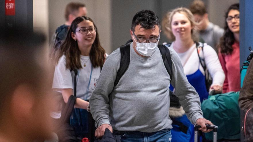 Un pasajero que llega a EE.UU. con una máscara para protegerse de coronavirus, el aeropuerto de Dulles, Washington, el 13 de marzo de 2020. (Foto: AFP)