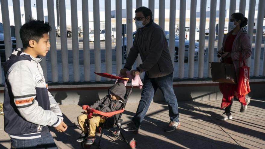 Los migrantes llevan mascarillas protectoras por el COVID-19, la frontera entre EE.UU. y México en Tijuana (México), 29 de febrero de 2020.