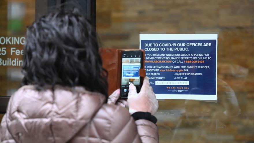 Una mujer toma foto de un letrero frente al cerrado Departamento de Trabajo de EE.UU., Nueva York, 25 de marzo de 2020. (Foto: AFP)