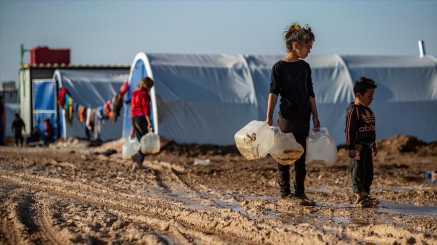 Niños sirios llevan bidones para llenarlos con agua en un campamento en las afueras de la ciudad de Al-Hasaka, 16 de diciembre de 2019. (Foto: AFP)