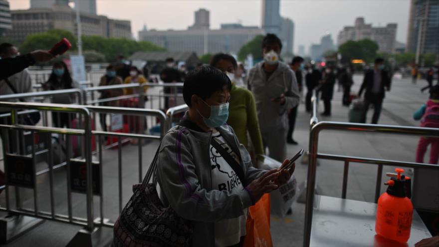 Personas con mascarillas revisan su código de salud de Wuhan frente a la estación de tren de Hankou en Wuhan, 8 de abril de 2020. (Foto: AFP)