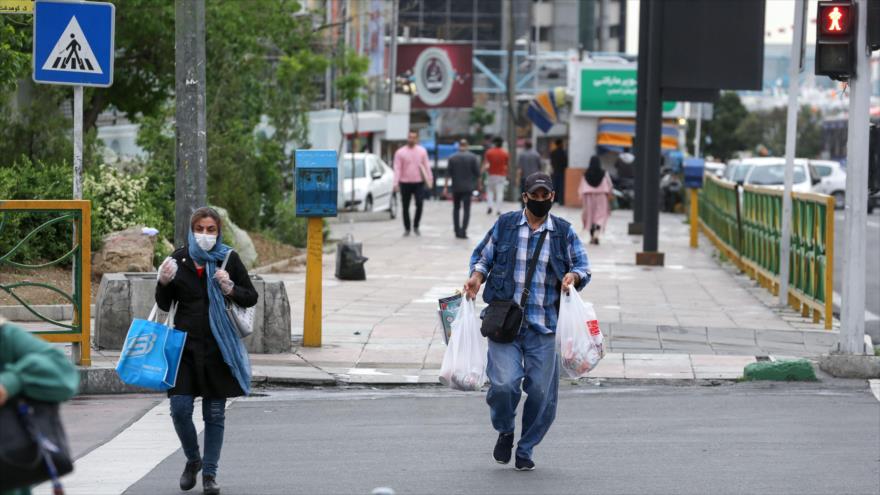 Ciudadanos iraníes con máscaras protectoras en medio de la pandemia COVID-19 cruzan una calle en Teherán, la capital, 26 de abril de 2020. (Foto: AFP)
