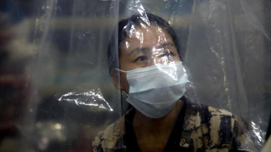 Una cajera trabaja detrás de una cortina de plástico improvisada como precaución contra la propagación del coronavirus, en Buenos Aires, Argentina.