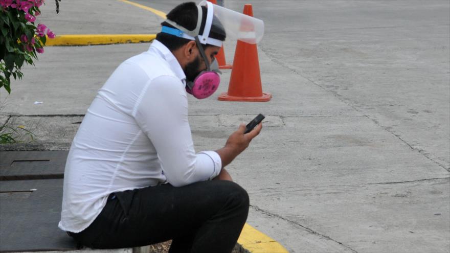 Hombre usa su teléfono móvil mientras espera fuera del Hospital General en la ciudad ecuatoriana de Guayaquil, 6 de mayo de 2020. (Foto: AFP)