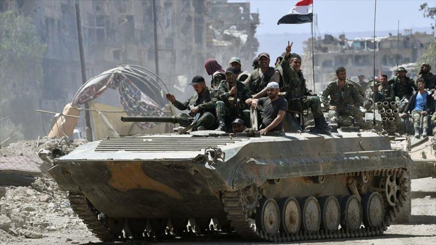 Soldados del Ejército sirio al borde de un tanque celebran victoria ante los terroristas en el campo de Yarmuk, al sur de Damasco.