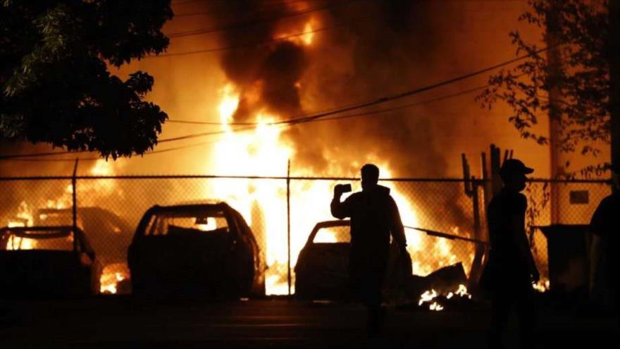 Dos personas observan un incendio provocado durante las protestas en Mineápolis (norte), 29 de mayo de 2020. (Foto: AP)