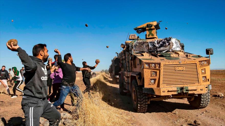 Civiles sirios arrojan piedras contra vehículos militares turcos, desplegados en la provincia siria de Al-Hasaka.