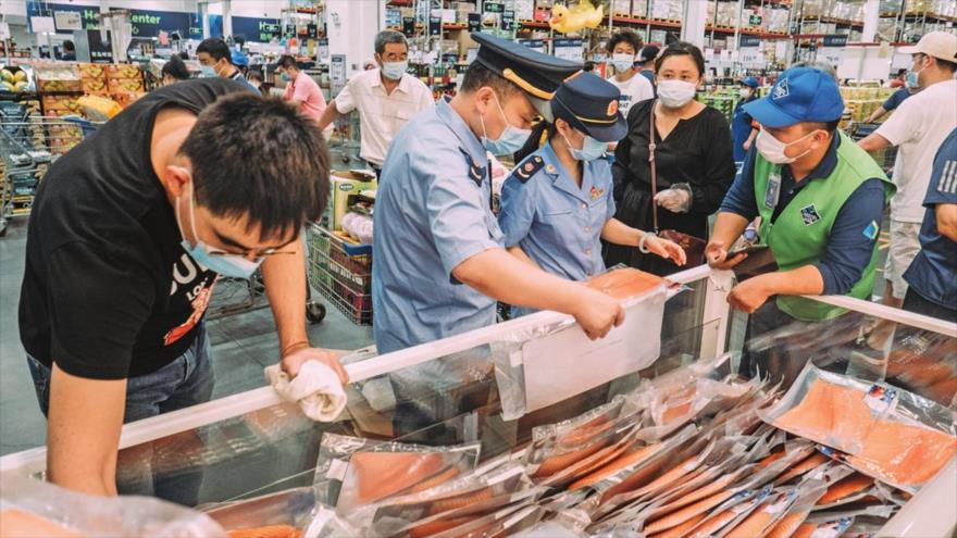 Los empleados de la Administración de Drogas y Alimentos revisan el salmón en una tienda en Pekín, la capital china, 13 de junio de 2020.