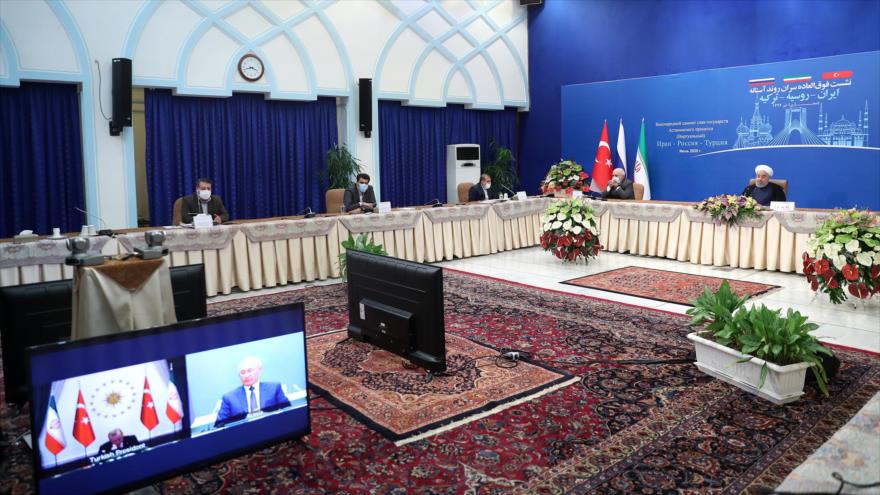 El presidente de Irán, Hasan Rohani (dcha.), en una videoconferencia con sus pares de Turquía y Rusia sobre la crisis en Siria, 1 de julio de 2020.