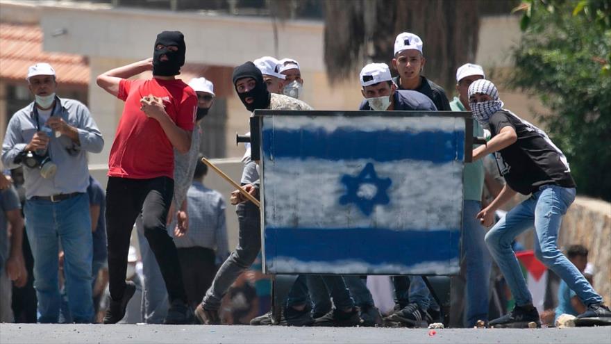 Manifestantes palestinos arrojan piedras a las tropas israelíes durante una protesta en la Cisjordania ocupada, 3 de julio de 2020. (Foto: AFP)