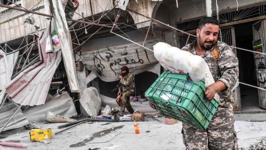 Milicianos armados saquean las tiendas en la región de Afrin, situada en el norte de la provincia siria de Alepo.