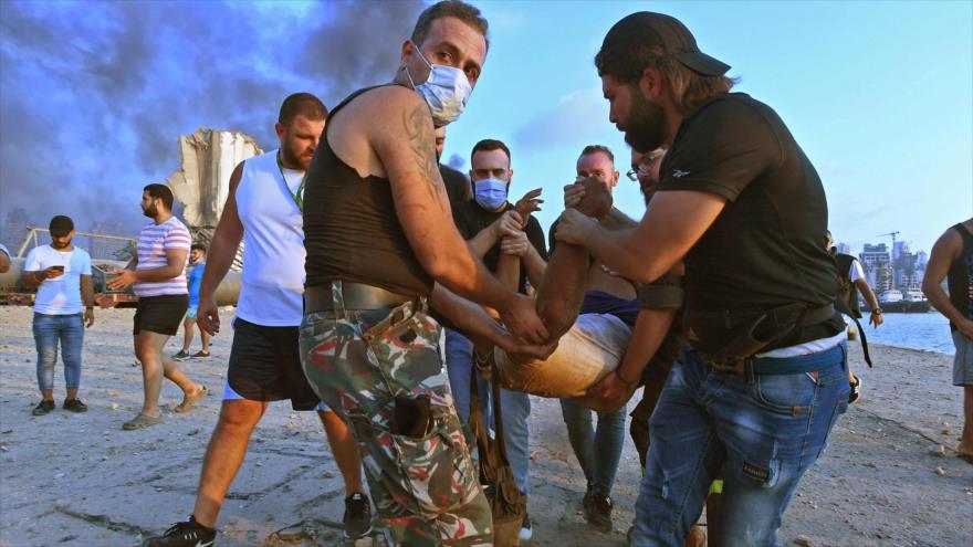 Ciudadanos libaneses ayudan a un hombre herido tras la potente explosión en el puerto de la capital libanesa, Beirut, 4 de agosto de 2020. (Foto: AFP)