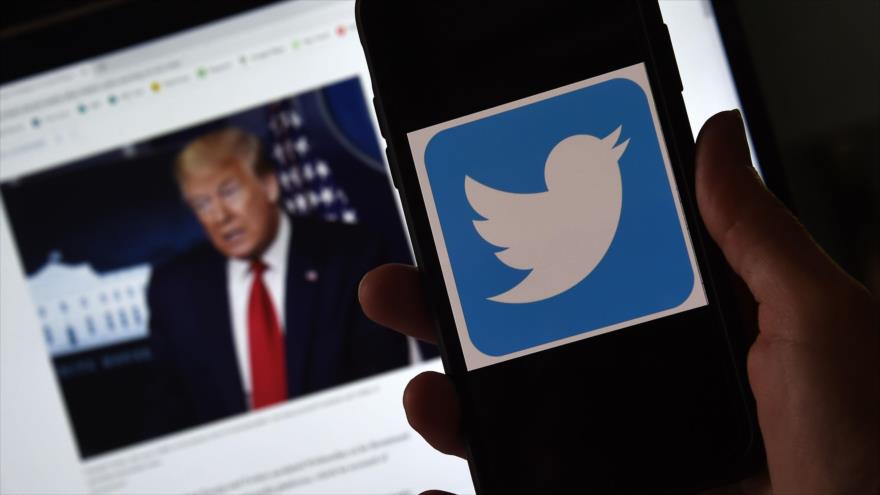 En la imagen aparece en primer término el logotipo de Twitter en un celular junto a una fotografía de Trump de fondo, 27 de mayo de 2020. (Foto: AFP)