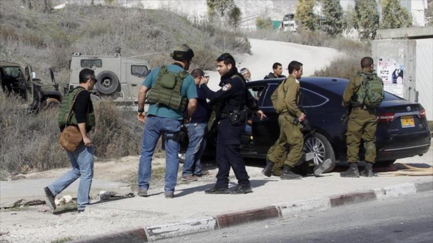 Fuerzas israelíes inspeccionan el coche de un colono que atropelló a un palestino cerca de la ciudad cisjordana de Nablus.
