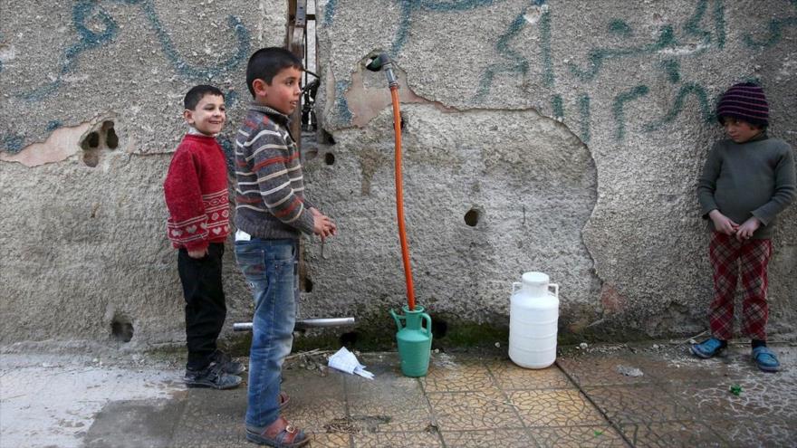 Varios niños recogen agua en la ciudad siria de Duma, cerca de Damasco.