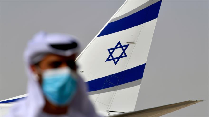 Un emiratí, delante de la aleta del avión de la aerolínea israelí El Al en el aeropuerto internacional de Abu Dabi, capital de EAU, 31 de agosto de 2020. (Foto: AFP)