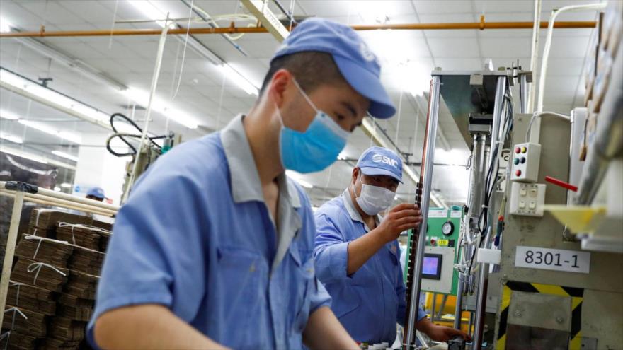 Empleados chinos con mascarilla durante su jornada laboral en una fábrica de la empresa de componentes SMC. (Foto: Reuters)
