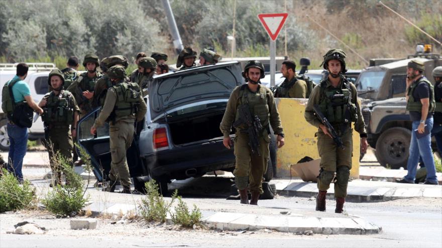 Soldados israelíes inspeccionan coche de un colono que atropelló a un palestino en la ocupada Cisjordania.