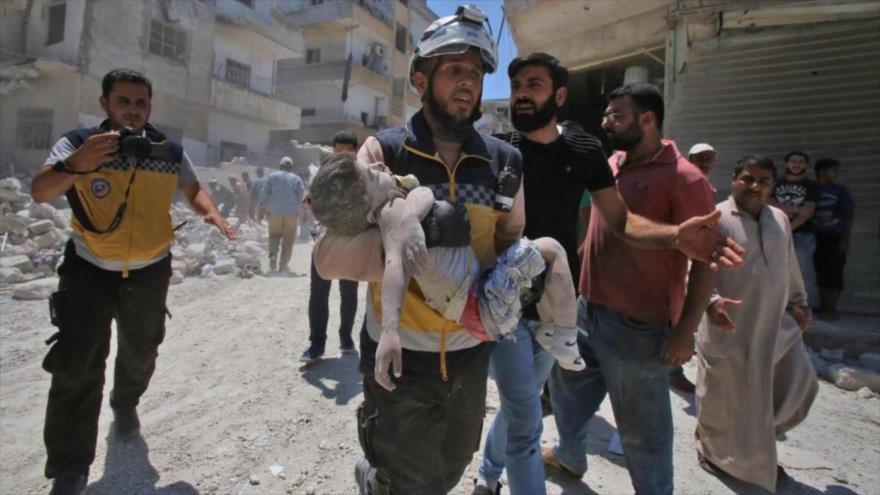 Un miembro de los llamados cascos blancos fotografiado con un niño muerto en sus brazos en una localidad en Idlib, Siria, 27 de julio de 2019. (Foto: AFP)