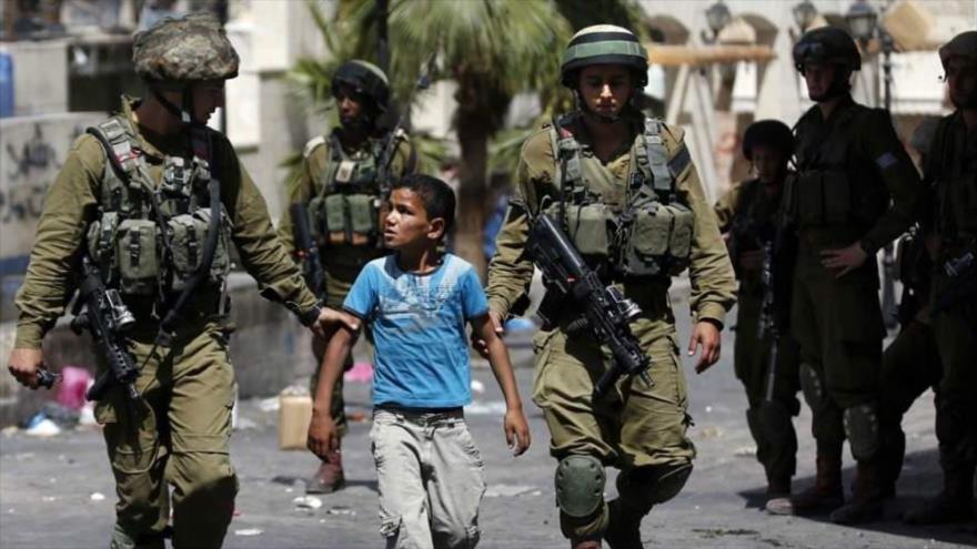 Soldados israelíes detienen a un niño en la Cisjordania ocupada.