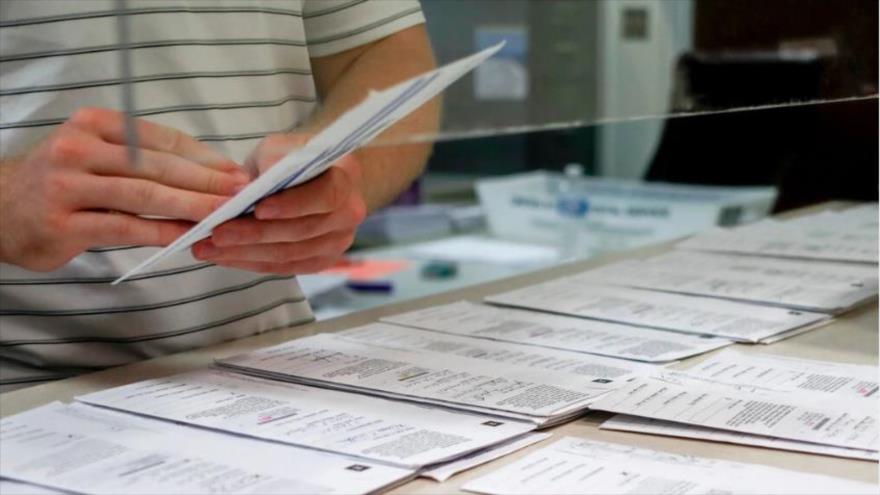 Un empleado federal de EE.UU. ordena boletos del sufragio emitidos por los estadounidenses y enviados por correo postal previo su escrutinio. 