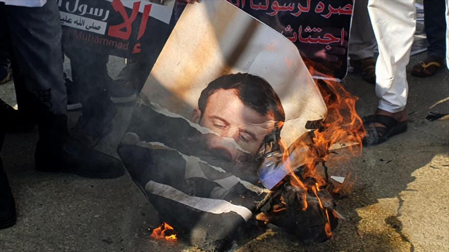 Manifestantes queman una foto del presidente francés, Emmanuel Macron, durante una protesta en Libia, 30 de octubre de 2020. (Foto: AFP)