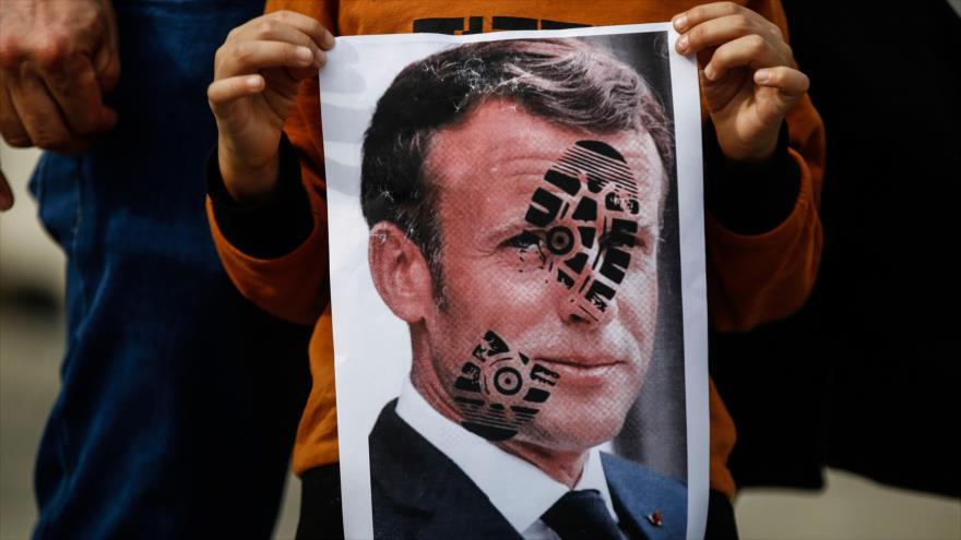 Un niño sostiene una foto del presidente de Francia, estampada con la marca de un zapato, durante una protesta en Estambul, Turquía, 25 de octubre de 2020.