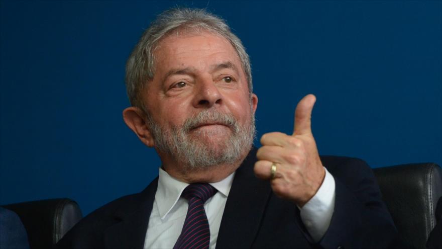 El expresidente de Brasil Luiz Inácio Lula da Silva levanta su pulgar en señal de victoria en una reunión.