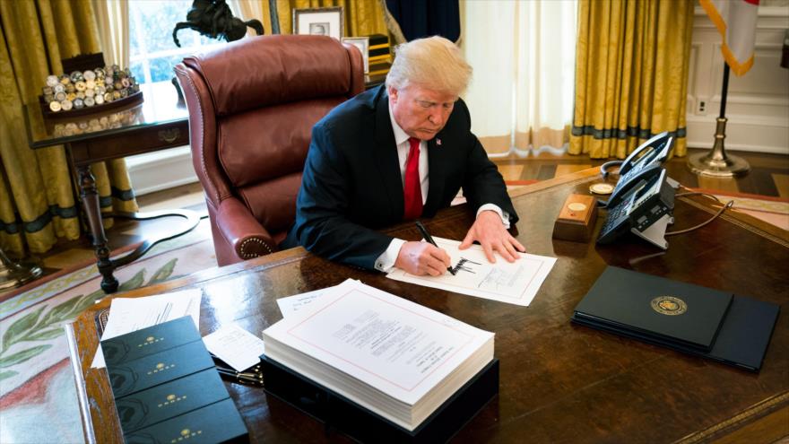 El presidente de EE.UU., Donald Trump, firma un documento en el Despacho Oval de la Casa Blanca.