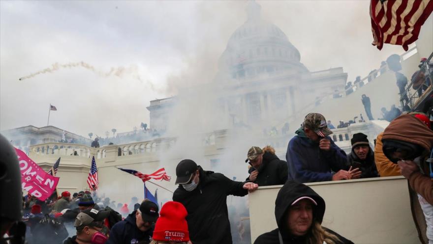 Partidarios de Trump se protegen el rostro para evitar inhalar los gases lacrimógenos lanzados por policías al frente del Capitolio de EE.UU., 6 de enero de 2021. (Foto: Reuters)