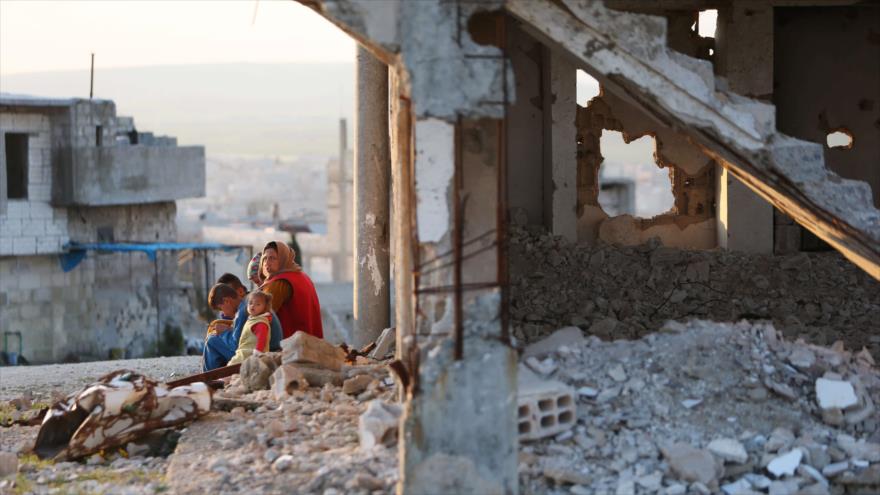 Una mujer sentada con niños sobre los escombros de un edificio destruido en Kobani, Siria, 3 de abril de 2019. (Foto: Reuters)