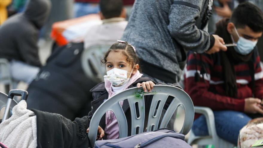 
Los palestinos enmascarados esperan cruzar al lado egipcio en el cruce fronterizo entre Gaza y Egipto, 24 de noviembre de 2020. (Foto: AFP)