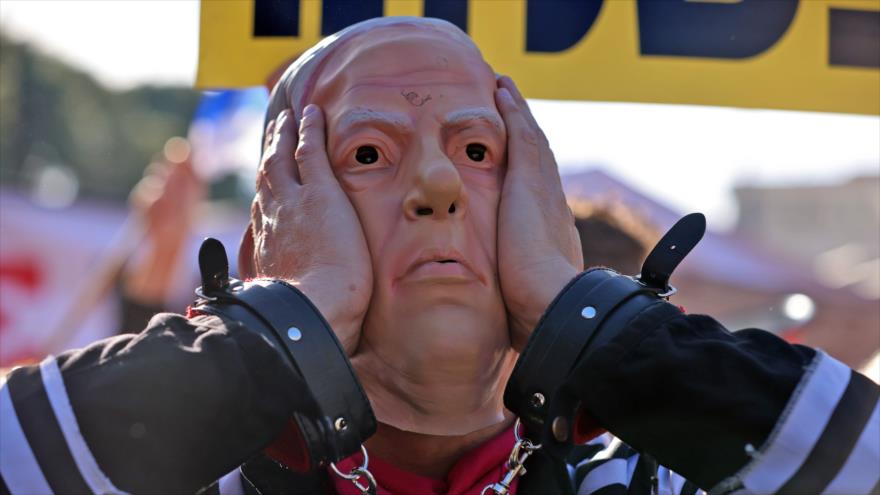 Un hombre con una máscara del premier israelí, Benjamín Netanyahu, en una manifestación frente a un tribunal en Al-Quds (Jerusalén), 8 de febrero 2021, (Foto: AFP)