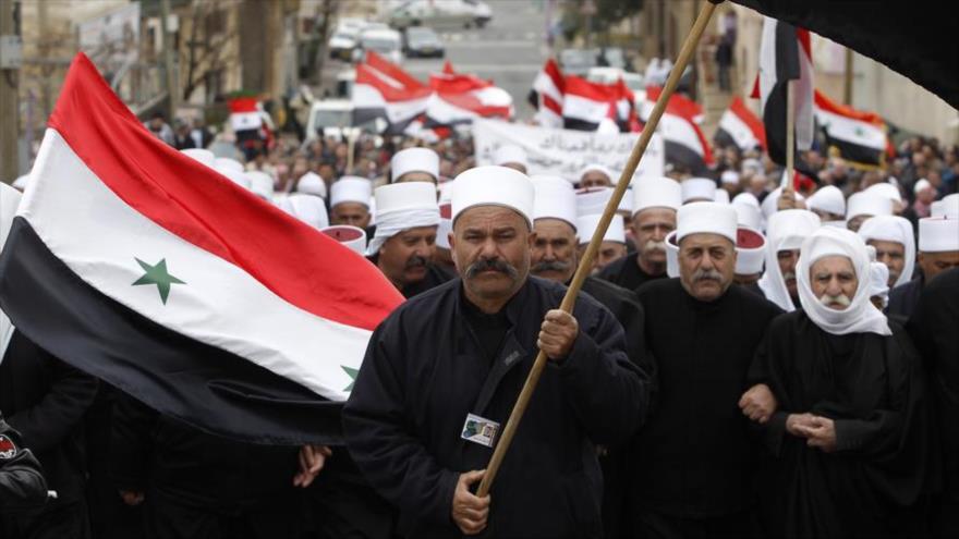 Los residentes del ocupado Golán sirio sostienen banderas de Siria en un mitin en la aldea drusa de Majdal Shams.