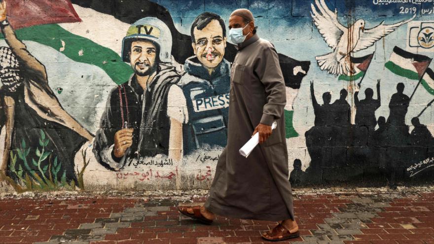 Un palestino pasa junto a un mural de periodistas asesinados en el 2014 en la ciudad de Gaza, Palestina, 4 de marzo de 2021. (Foto: AFP)