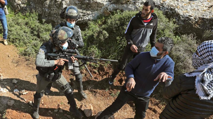 Soldados israelíes apuntan con su arma hacia un manifestante palestino en la ocupada Cisjordania, 5 de marzo de 2021. (Foto: AFP)