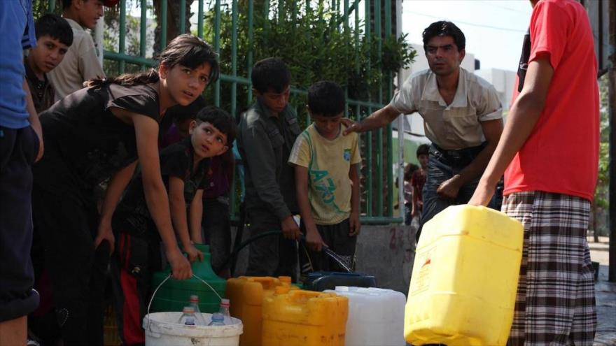 Niños palestinos llenan bidones con agua potable de un grifo público en la Franja de Gaza. (Foto: Midel East Monitor)