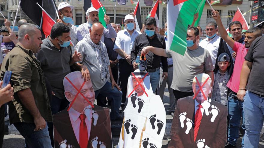 Palestinos prenden fuego a imágenes de izq. a dcha.: el premier israelí, el príncipe heredero emiratí y el expresidente de EE.UU., 14 de agosto de 2020. (Foto: AFP)