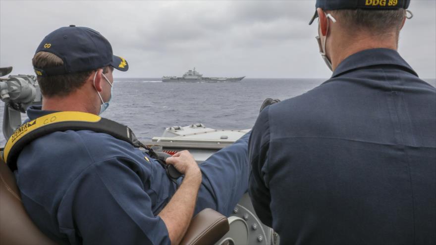 El capitán naval estadounidense Robert Bridges (izda.), junto a su asistente, observan el destructor chino Liaoning, desde el USS MustinUSS Mustin.