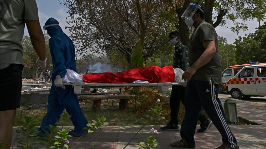 Llevan el cuerpo de una víctima que murió por Covid-19 en un campo crematorio en Nueva Delhi, 4 de mayo de 2021. (Foto: AFP)