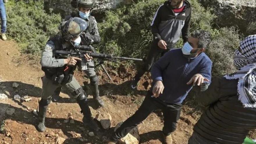 Un soldado israelí apunta con su arma a un manifestante palestino durante una protesta contra los asentamientos israelíes ilegales en Beit Dajan, cerca de Nablus, 5 de marzo de 2021. (Foto: AFP)
