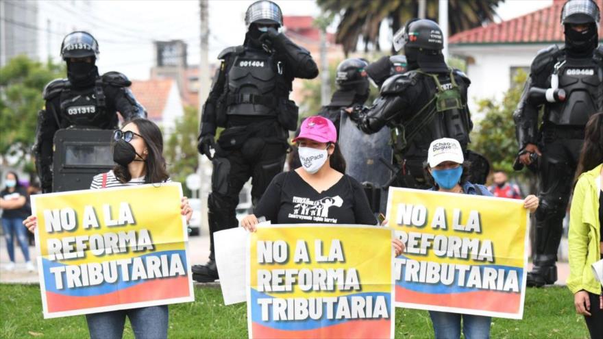Mujeres colombianas sostienen pancartas que dicen “No a la reforma tributaria” durante una protesta antigubernamental.