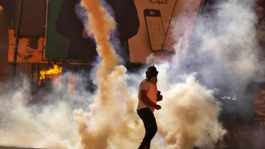 Un manifestante palestino se encuentra en medio de gases lacrimógenos disparados por las fuerzas de israelíes en Cisjordania. 8 de mayo de 2021. (Foto: AFP)