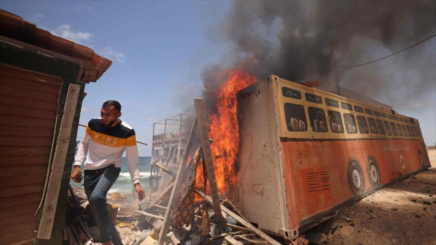Un hombre palestino huye tras un ataque de Israel en la Franja de Gaza, 17 de mayo de 2021. (Foto: AFP)