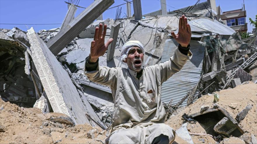 Un palestino sentado frente a los escombros de su casa después de un ataque aéreo israelí en el sur de la Franja de Gaza, 16 de marzo de 2021. (Foto: AFP)