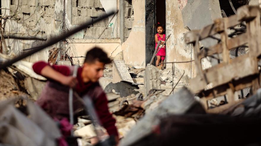 Un joven palestino busca en las ruinas de un edificio destruido durante los atentados israelíes en la ciudad de Gaza, 21 de mayo de 2021. (Foto: AFP)