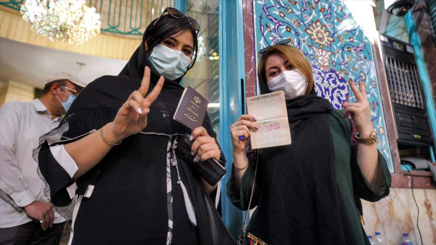 Mujeres iraníes muestran sus documentos de identidad nacional sellados tras votar en Teherán, capital de Irán, 18 de junio de 2021. (Foto: AFP)