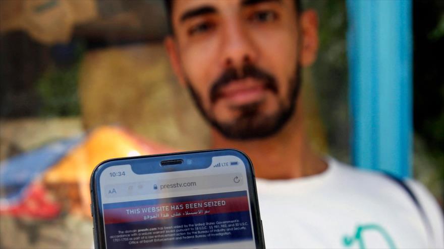 Un hombre iraní muestra en su teléfono móvil una nota de bloqueo por parte de EE.UU. al sitio web de Press TV, Teherán, 23 de junio de 2021. (Foto: AFP)