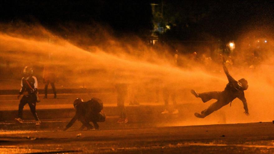 Un manifestante cae al suelo al ser alcanzado por un cañón de agua de un camión antidisturbios durante los enfrentamientos con la Policía en Bogotá, Colombia, 12 de junio de 2021.