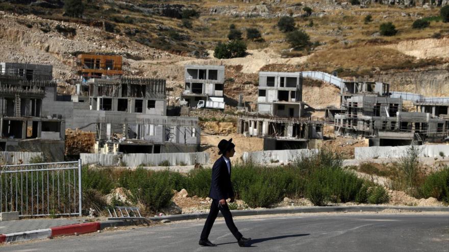 Un colono israelí pasa junto a los sitios de construcción de asentamientos ilegales en la Cisjordania ocupada, 30 de junio de 2020. (Foto: Reuters)